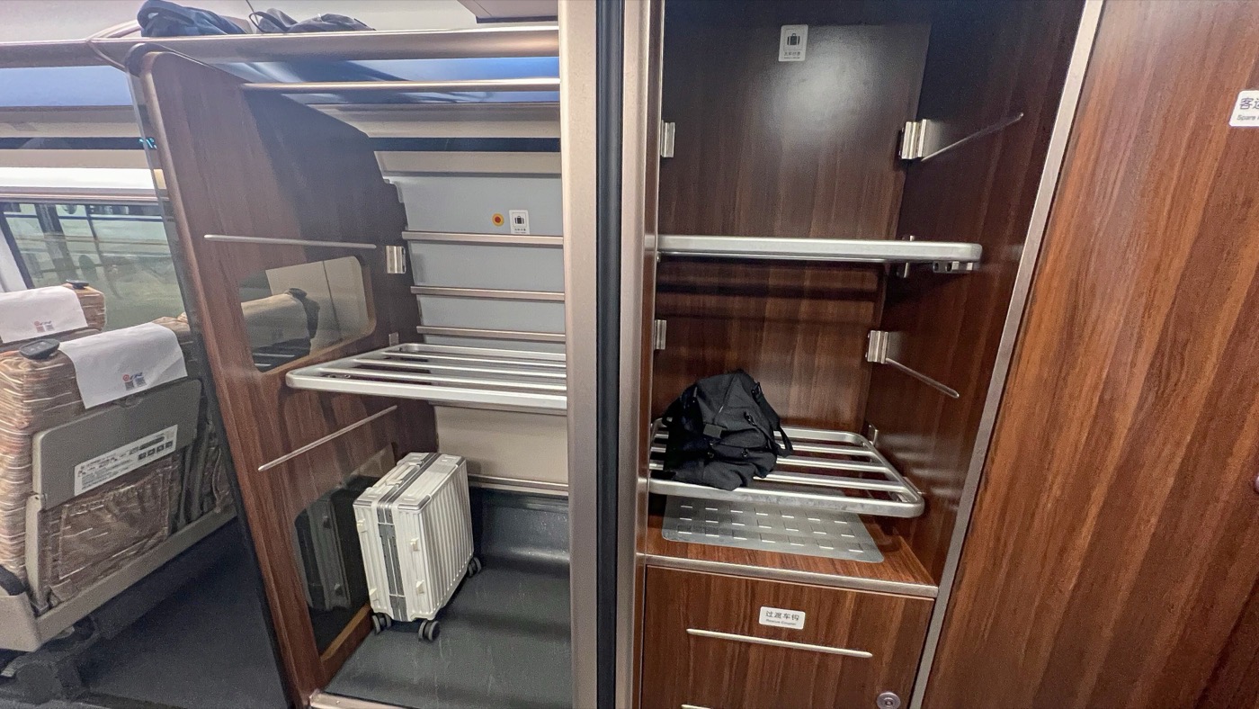 Luggage racks at the end of a Chinese high-speed train carriage, holding a suitcase and a backpack